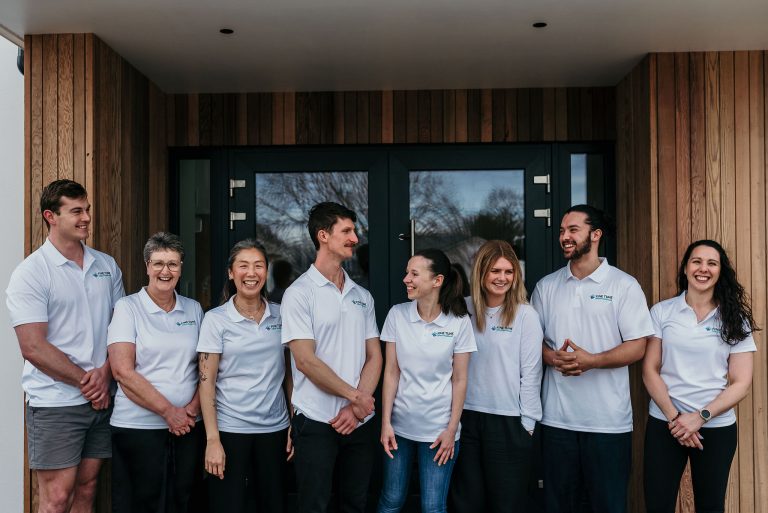 Team of osteopaths at Fine Tune Allied Healthcare standing together outside the clinic, smiling.