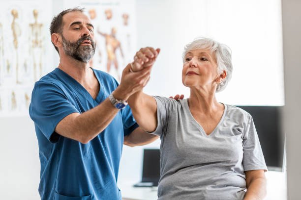 Therapist assisting a senior female patient in recovery from joint pain