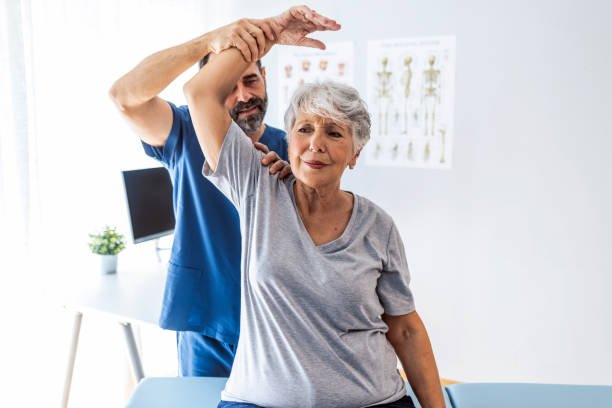 Osteopath assessing elderly woman's shoulder mobility