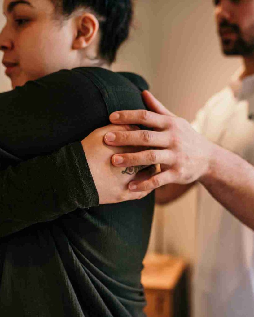 Osteopath guiding a patient through a shoulder stretch.